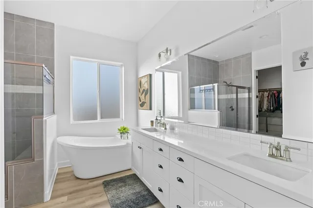 a bathroom with a bathtub a double vanity sink and a large mirror
