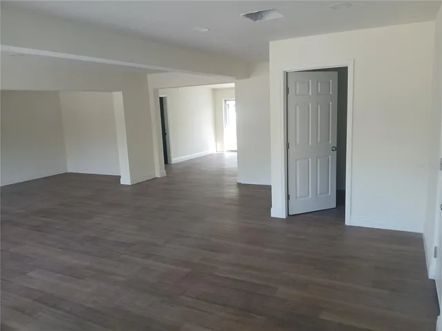 a view of an empty room with wooden floor & closet