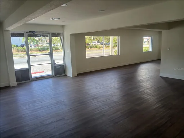 an empty room with wooden floor and windows