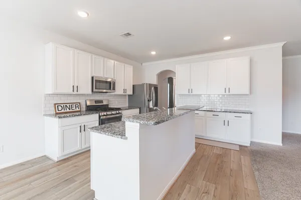 a kitchen with granite countertop a sink a counter top space stainless steel appliances and cabinets
