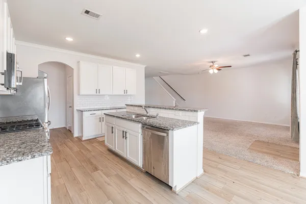 a kitchen with granite countertop a sink stove and cabinets