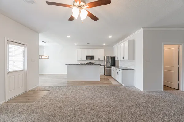 a view of a kitchen with wooden floor and a ceiling fan