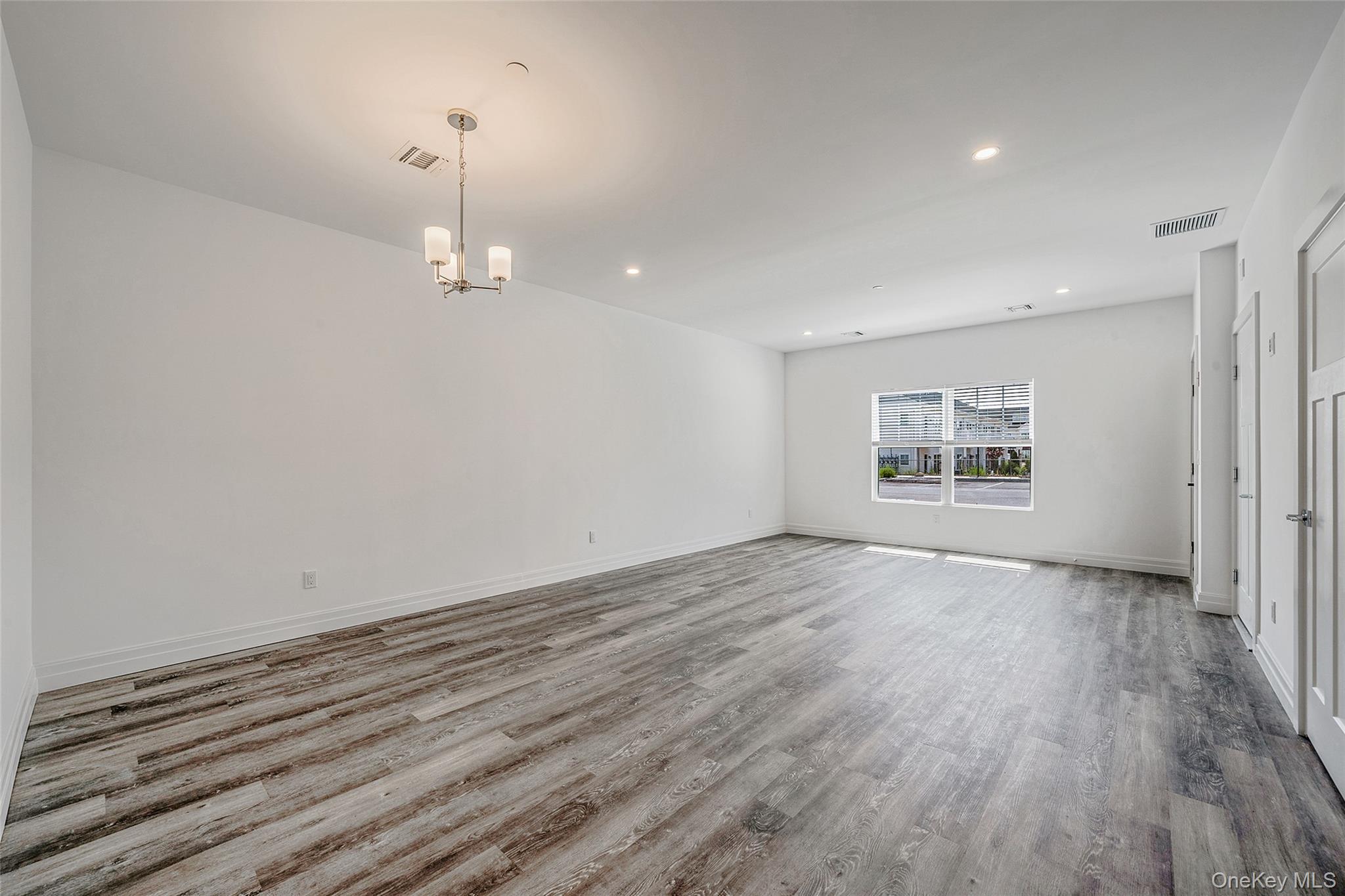 103 Dover Street Central Islip, NY 11722 - Photo 11 of 45 Spare room with wood finished floors, recessed lighting, and a chandelier