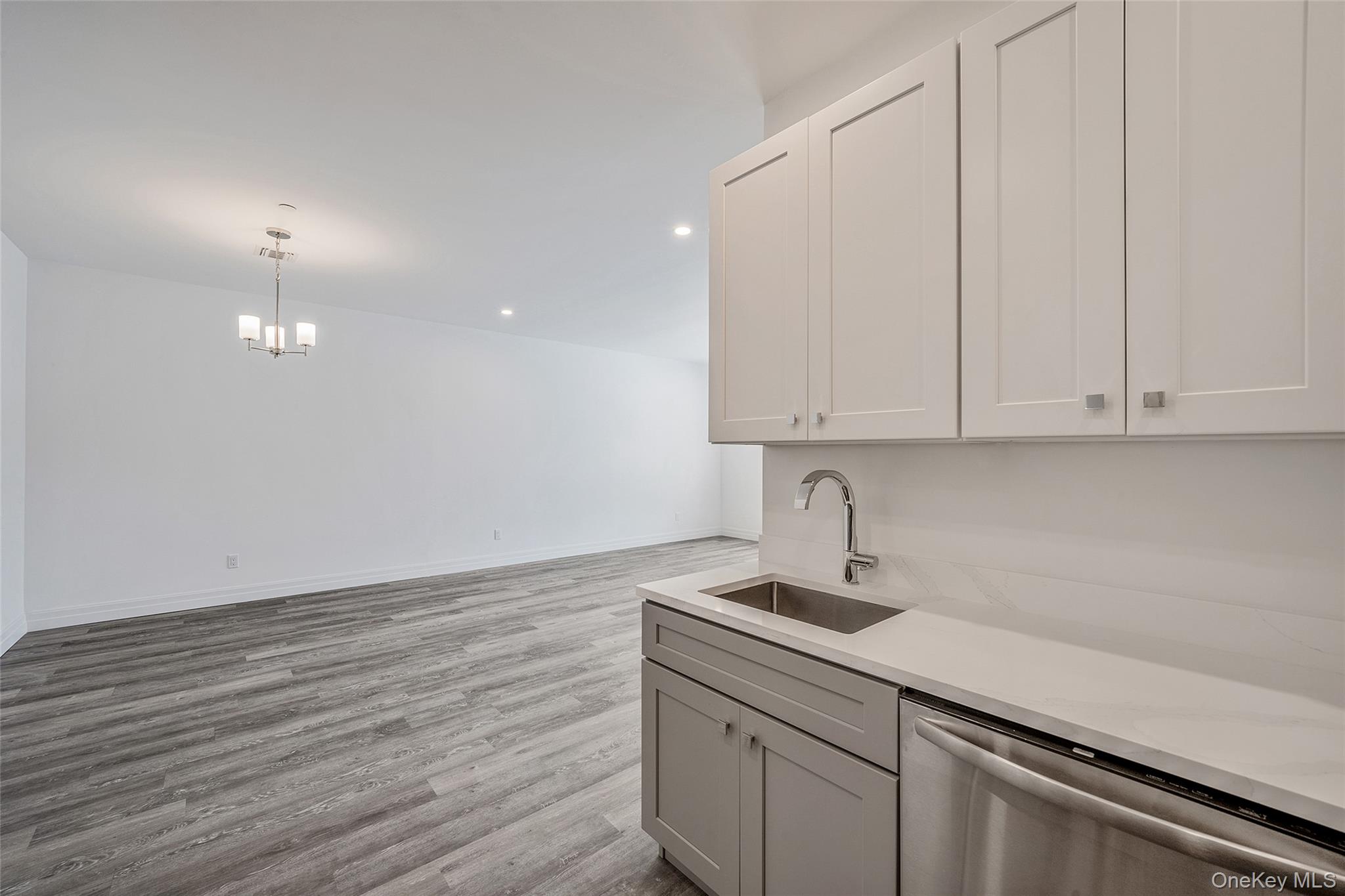 103 Dover Street Central Islip, NY 11722 - Photo 14 of 45 Kitchen featuring stainless steel dishwasher, light wood-type flooring, decorative light fixtures, recessed lighting, and light stone countertops