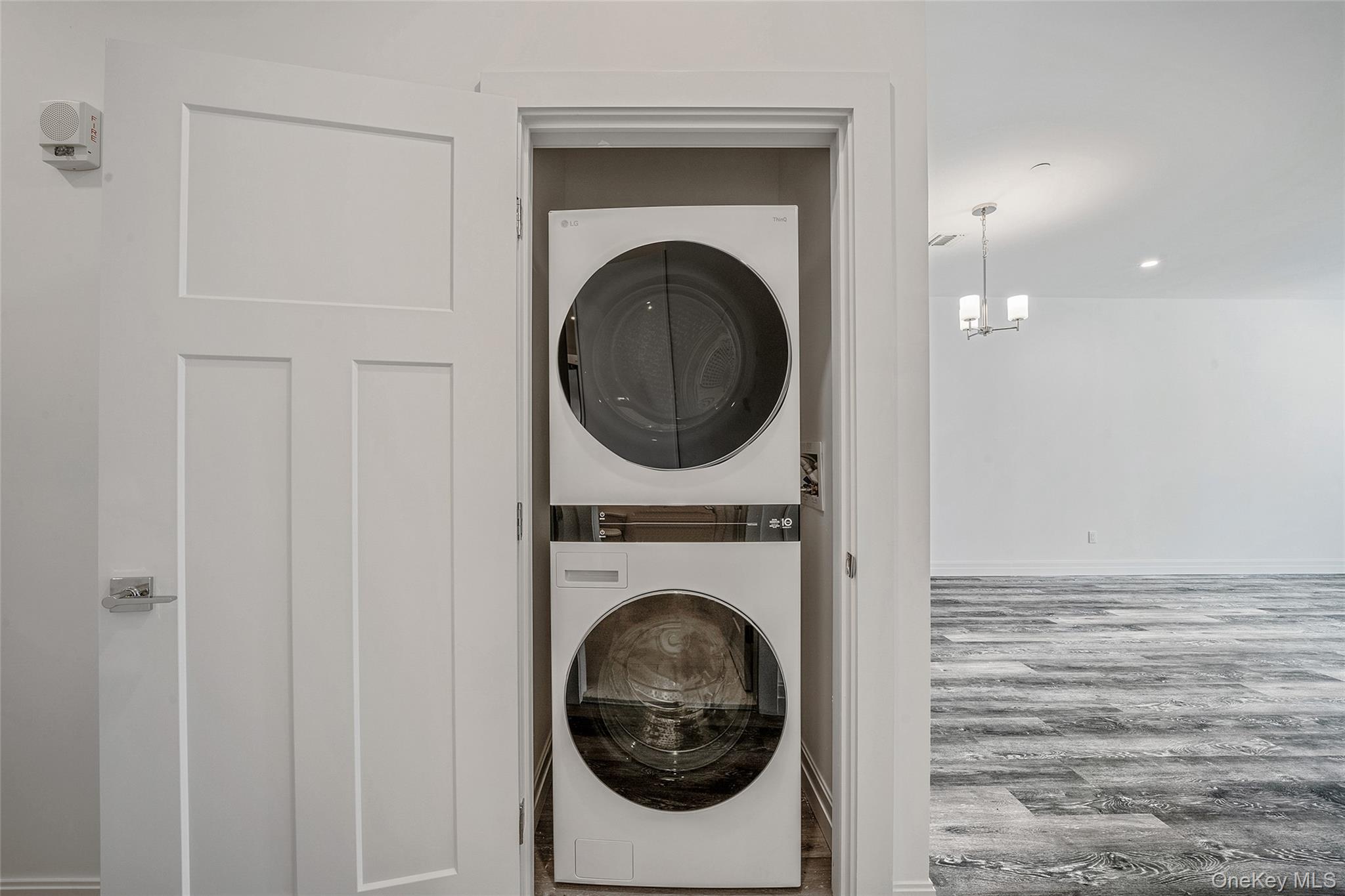 103 Dover Street Central Islip, NY 11722 - Photo 15 of 45 Laundry room featuring wood finished floors, stacked washer / drying machine, and a chandelier