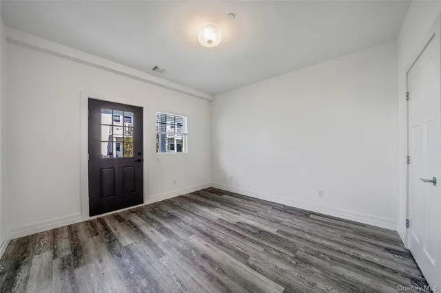 an empty room with wooden floor and window