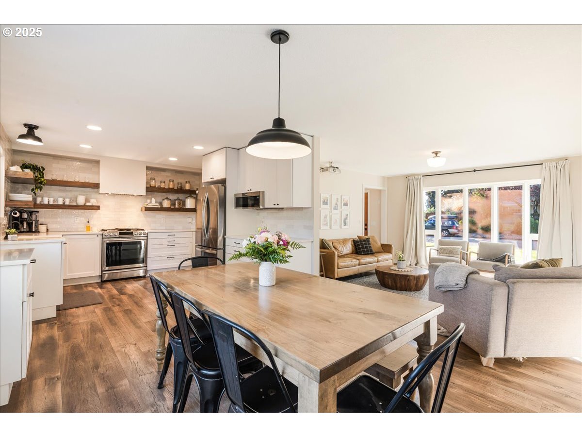 1200 Elm Lane Newberg, OR 97132 - Photo 9 of 32 a kitchen with stainless steel appliances kitchen island granite countertop a stove a refrigerator a kitchen island a dining table and chairs with wooden floor