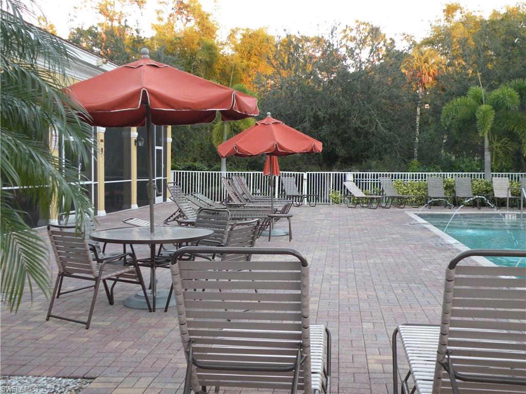 4440 Botanical Pl Circle, Unit 404 Naples, FL 34112 - Photo 11 of 11 a patio with a table and chairs under an umbrella