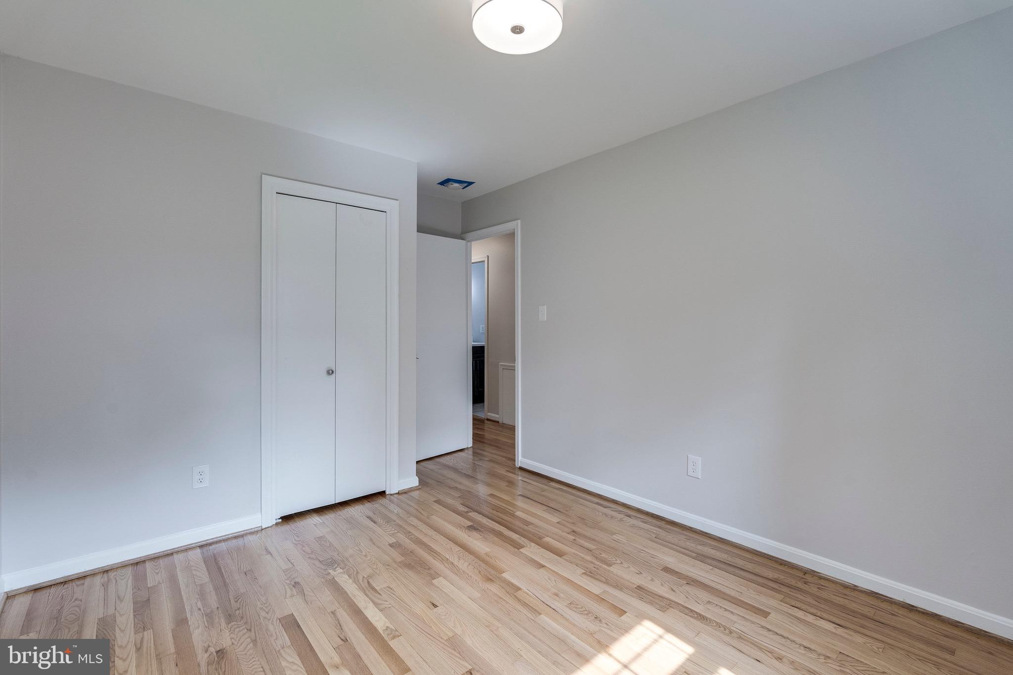 9808 Brixton Lane Bethesda, MD 20817 - Photo 20 of 24 a view of an empty room with wooden floor and a window