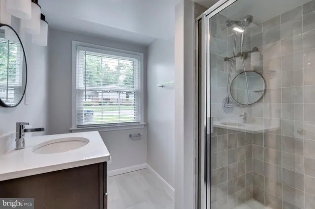 a bathroom with a granite countertop sink a mirror and a shower