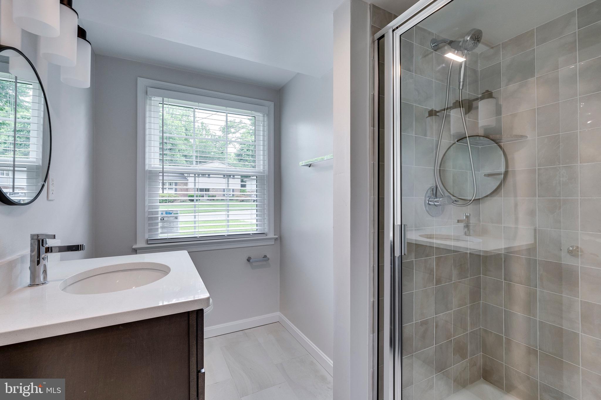 9808 Brixton Lane Bethesda, MD 20817 - Photo 6 of 24 a bathroom with a granite countertop sink a mirror and a shower