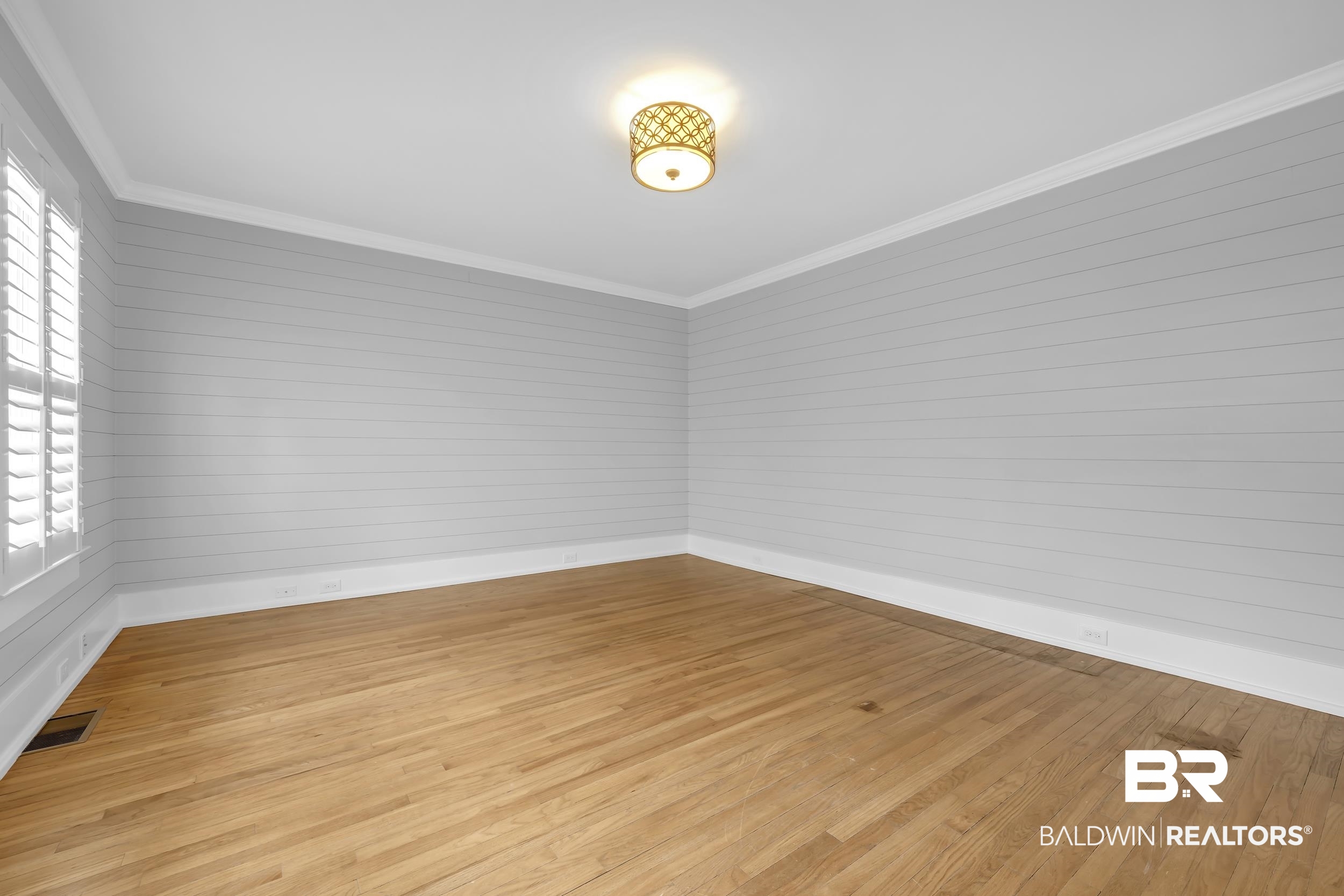 43199 Pine Grove Road Bay Minette, AL 36507 - Photo 54 of 71 Room featuring hardwood flooring, white crown molding, light gray shiplap walls, a window with plantation shutters, and a decorative semi-flush mount light fixture