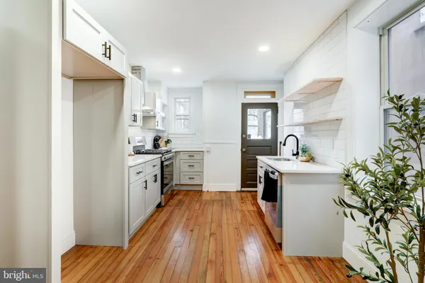 a kitchen with sink a refrigerator and wooden floor