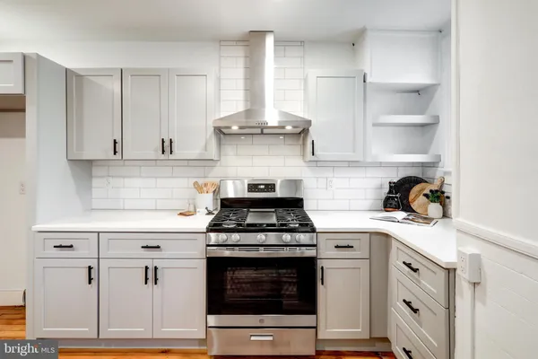 a kitchen with stainless steel appliances granite countertop a stove and white cabinets