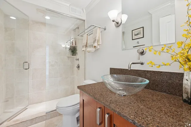 a bathroom with a granite countertop sink a toilet a mirror and shower