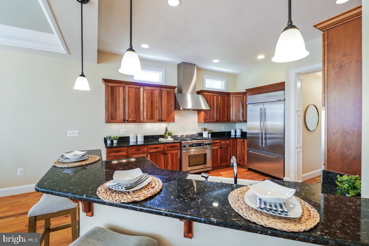 217 Talahi Road Southeast Vienna, VA 22180 - Photo 18 of 63 a kitchen with stainless steel appliances granite countertop a stove a refrigerator a sink a dining table and chairs with wooden floor