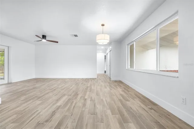 a view of an empty room with a window and wooden floor