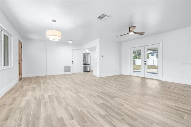 an empty room with wooden floor ceiling fan and windows