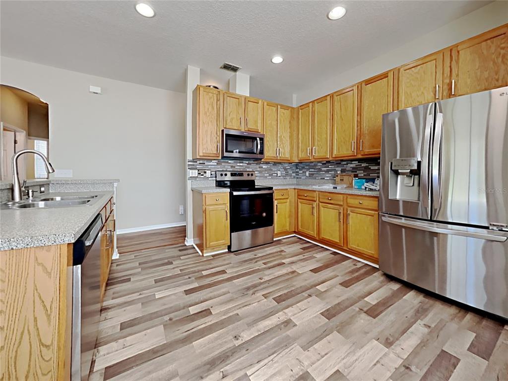 14136 Bradbury Road Orlando, FL 32828 - Photo 15 of 24 a kitchen with stainless steel appliances granite countertop a sink stove refrigerator and cabinets