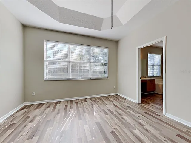 an empty room with wooden floor cabinet and windows