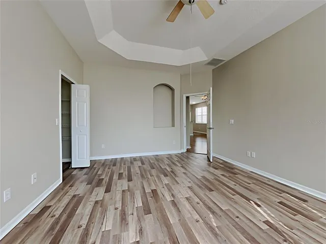 a view of empty room with wooden floor and fan