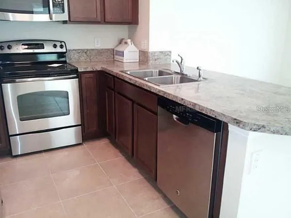 a kitchen with granite countertop a sink stove and cabinets