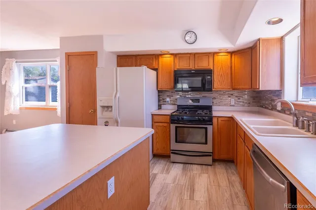 a kitchen with stainless steel appliances granite countertop a sink a stove and a wooden floors