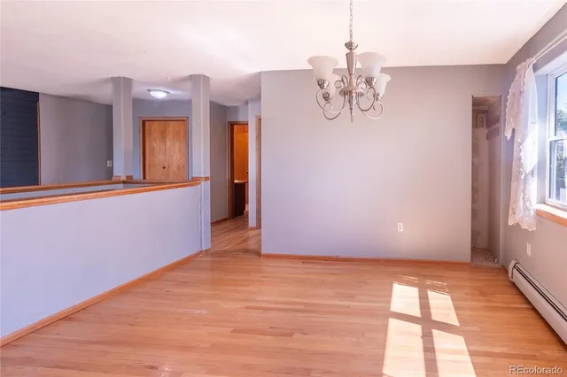 a view of an empty room with wooden floor and a ceiling fan