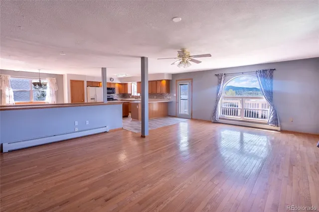 a living room with stainless steel appliances furniture a fireplace and wooden floor