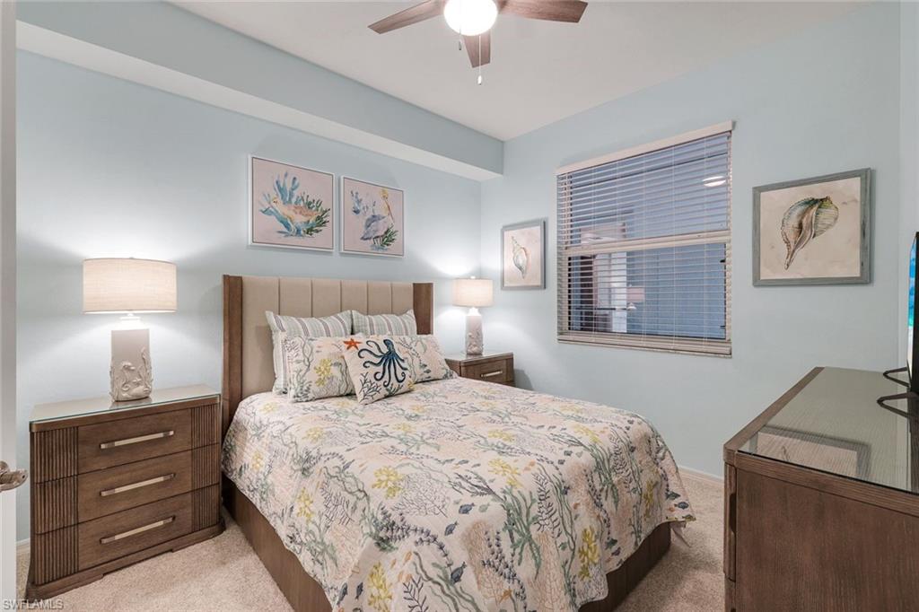 460 Launch Circle, Unit 202 Naples, FL 34108 - Photo 14 of 34 a bedroom with a bed and a lamp on dresser