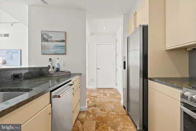 a kitchen with stainless steel appliances granite countertop a sink and a refrigerator