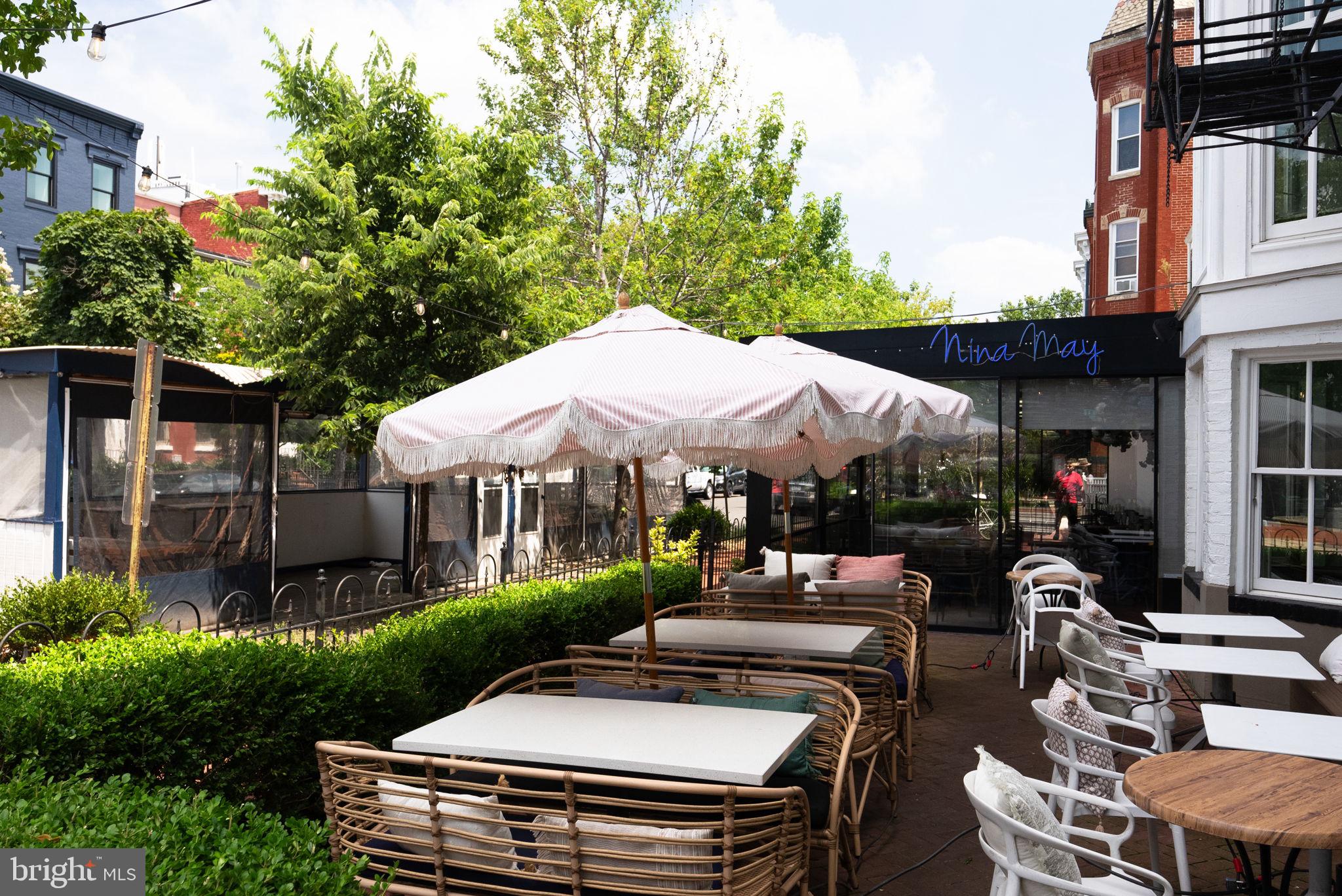 1300 13th Street Northwest, Unit 408 Washington, DC 20005 - Photo 46 of 47 a view of a patio with couches table and chairs under an umbrella with a small yard