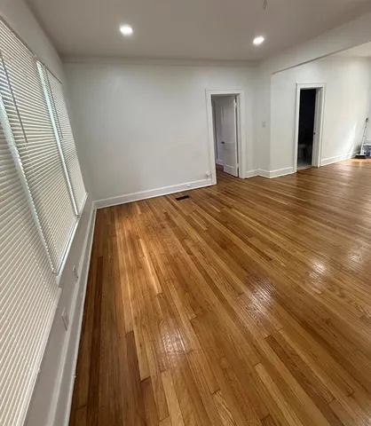 a view of an empty room with wooden floor and entryway