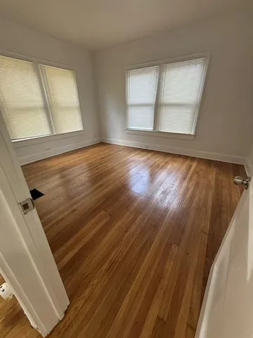 a view of an empty room with wooden floor and window