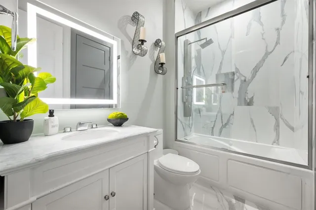 a bathroom with a granite countertop sink a toilet and shower