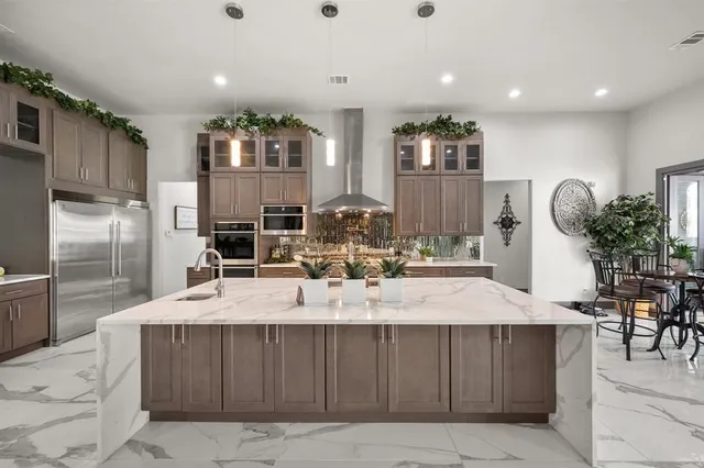 a large kitchen with granite countertop a large counter top stainless steel appliances and cabinets