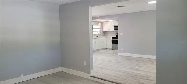 a view of an empty room with wooden floor and a window