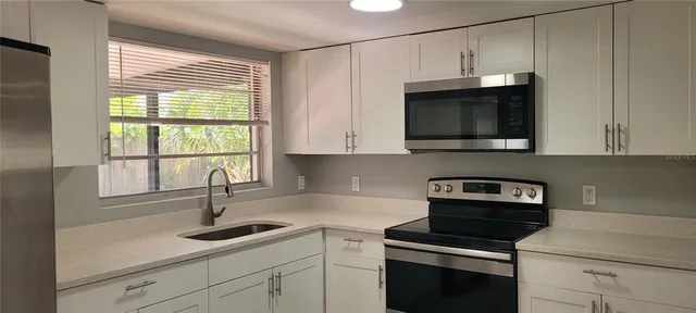 a kitchen with white cabinets and a window