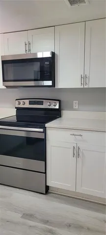 a view of a kitchen with a sink wooden cabinets and a refrigerator