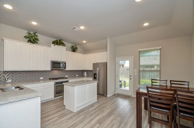 a kitchen with a sink white cabinets and stainless steel appliances