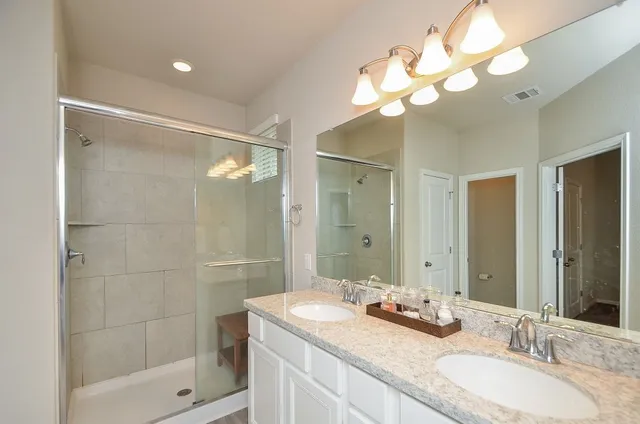 a bathroom with a granite countertop sink a mirror and a shower
