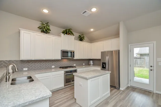 a kitchen that has a sink cabinets counter space and appliances
