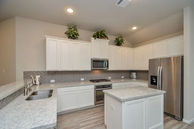 a kitchen with a refrigerator sink and white cabinets