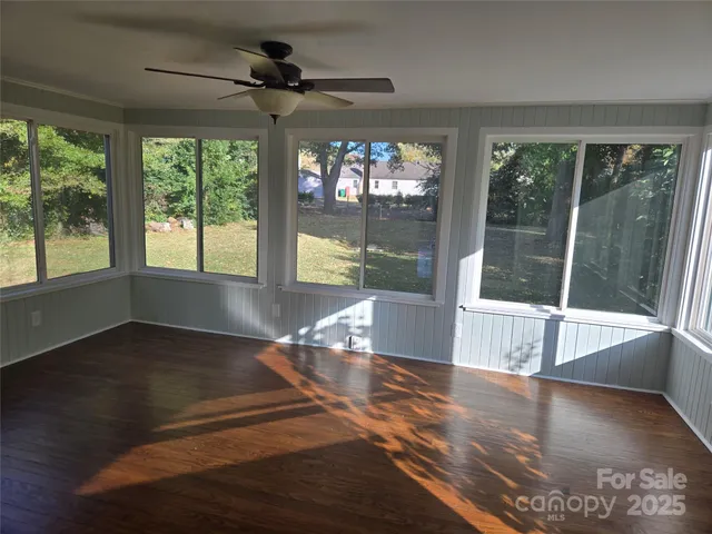 a view of empty room with wooden floor and fan