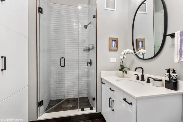 a bathroom with a sink a mirror a vanity and a shower
