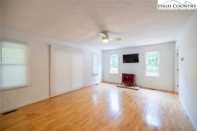 an empty room with windows and ceiling fan