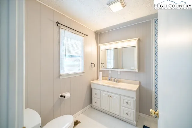 a bathroom with a granite countertop toilet a sink and a mirror