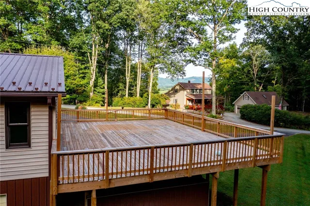 a view of a backyard with table and chairs potted plants and large tree