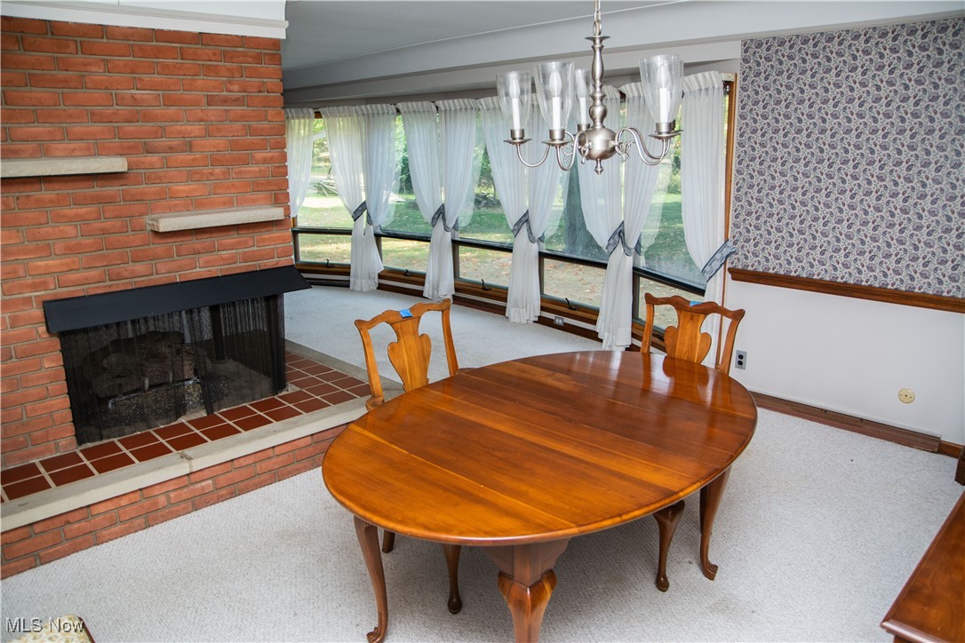 10050 New Buffalo Road Canfield, OH 44406 - Photo 12 of 49 Dining area with a brick fireplace, a notable chandelier, and light carpet