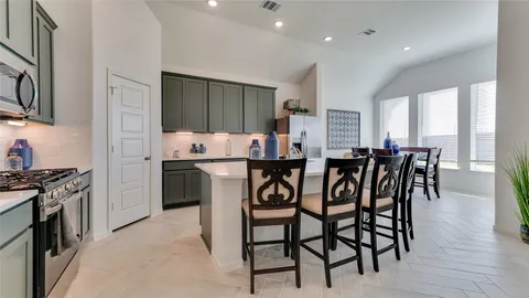 a kitchen with stainless steel appliances a table chairs refrigerator and microwave